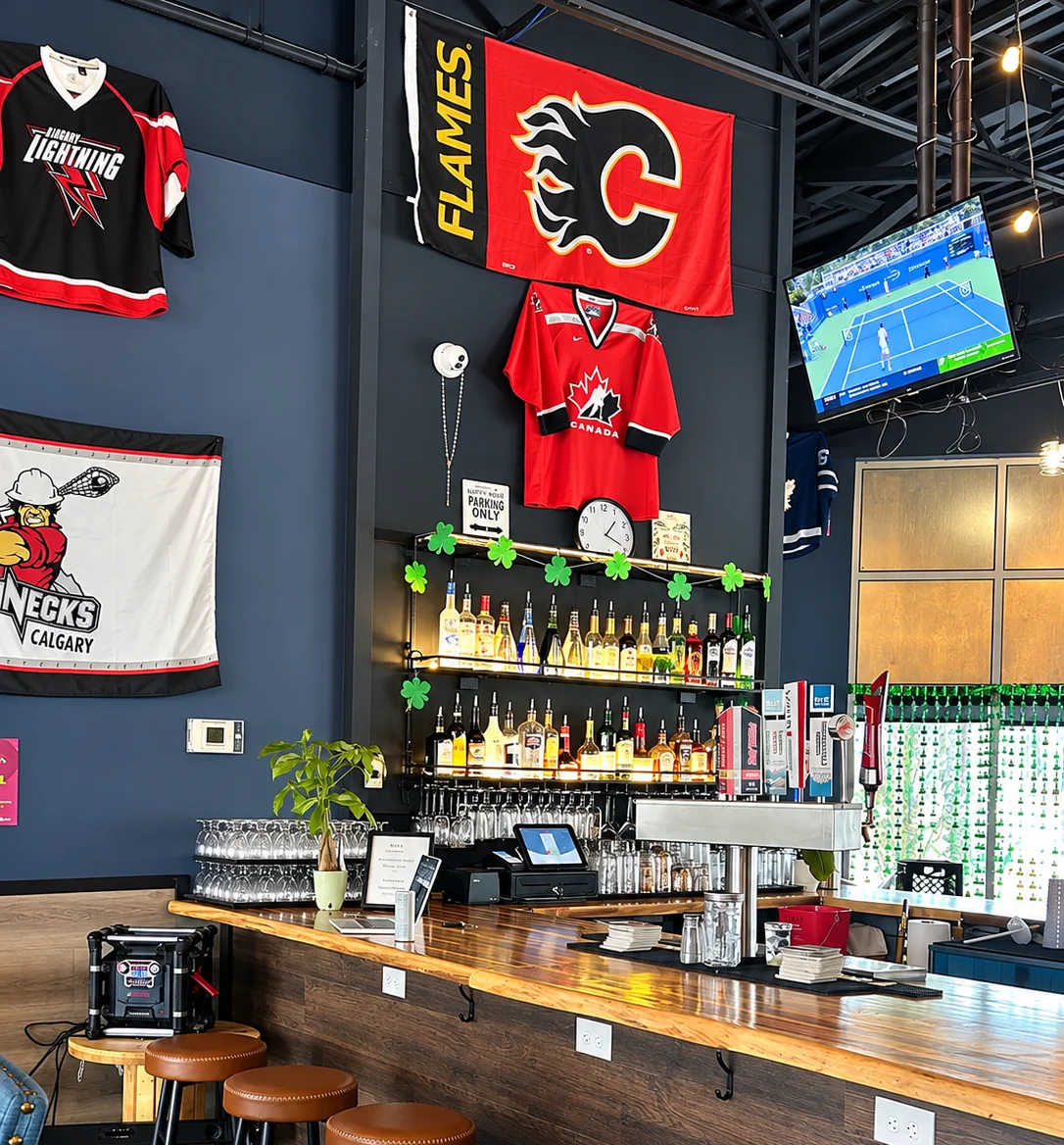 Bar counter with stools under hockey jerseys and a Calgary Flames banner