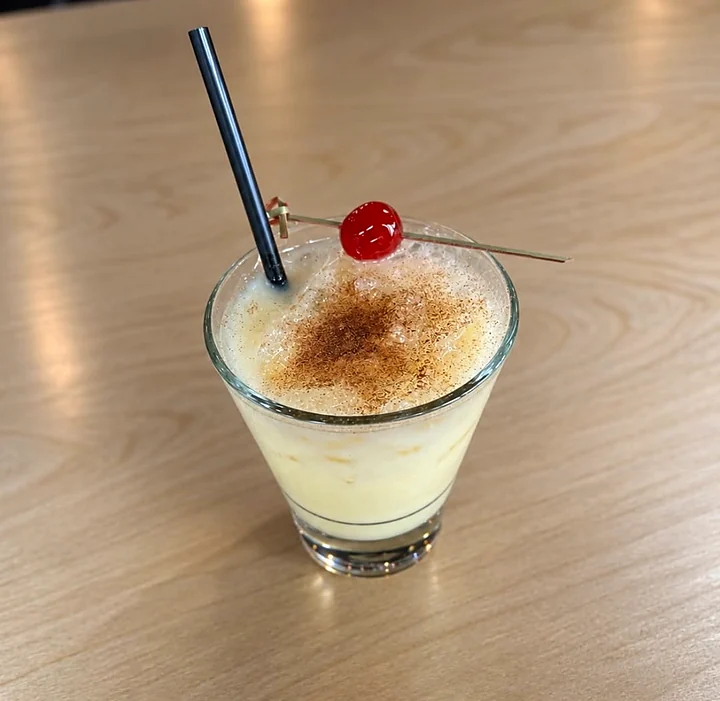 Creamy eggnog cocktail with cinnamon and a cherry